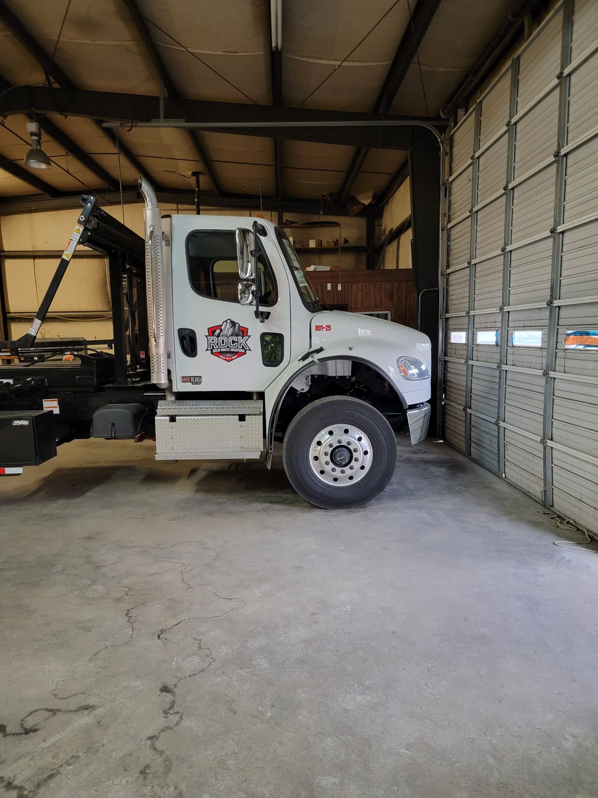 Truck with tarp system covering a loaded dumpster